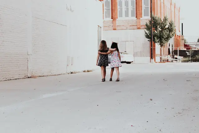 2 kleine Mädchen gehen ineinander verschlungen auf einer leeren Straße