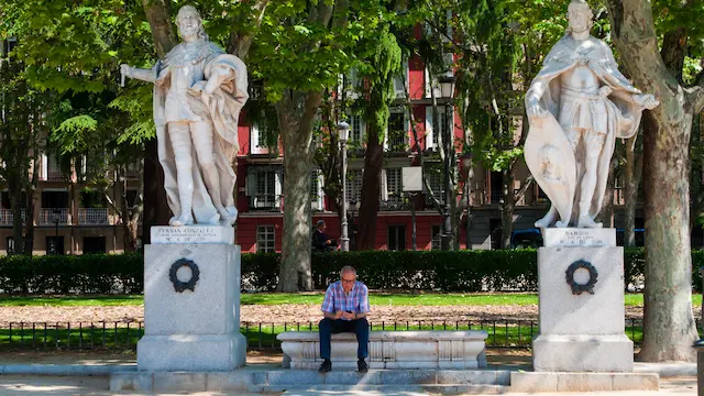 Mann sitzt zwischen zwei großen Statuen