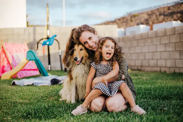 Glückliche Mutter mit kleiner Tochter und Schäferhund
