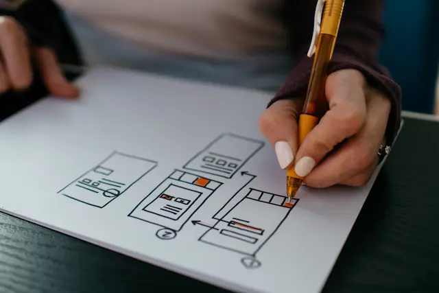 Frau zeichnet UI Design auf Notizblock