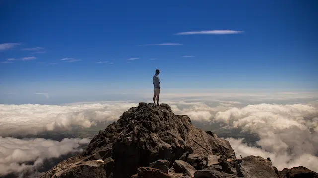 Mann steht auf einem Gipfel