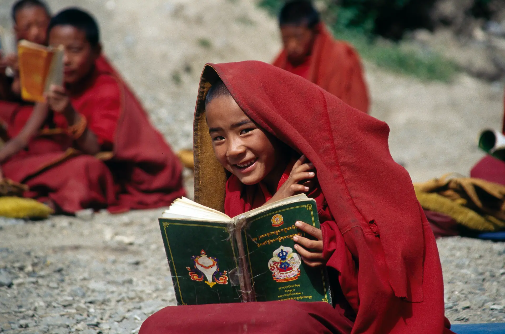 Tibetischer Junge in Mönchsgewand liest ei einem Buch